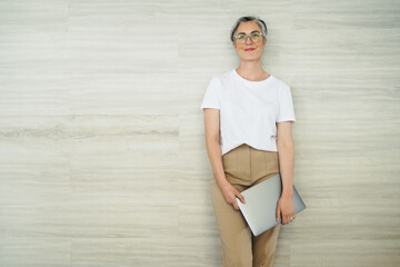 Cheerful businesswoman standing against a wall in an office