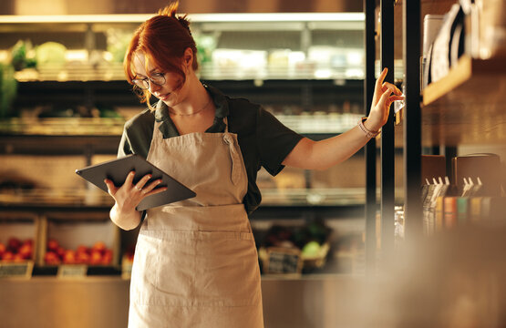 Supermarket Owner Using A Digital Tablet In Her Shop