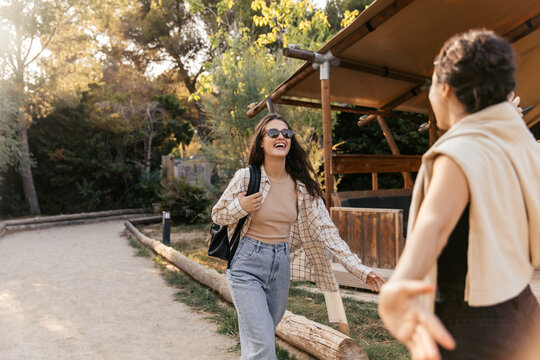 Joyful young caucasian girls go to meet each other spending leisure time in nature. Brunettes wear casual clothes on vacation. Spring season concept