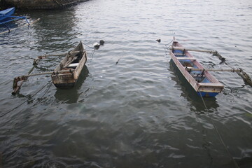 two traditional Indonesian fishing boats leaning on the beach.