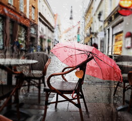  rain drops Autumn yellow leaves  on window view on street with cafe table and umbrella in Tallinn old town travel to Estonia 