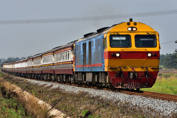 Fototapeta premium Passenger train by diesel locomotive on the railway in Thailand