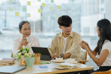 Group of Asian business people meeting, consulting and planning business on investment and market analysis for business development there are various analytical data document and using a laptop.