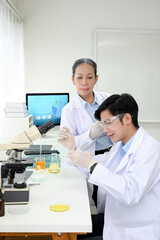 Obraz premium A professional Asian-aged female scientist instructs her new young male scientist in the lab