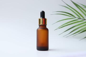 Amber glass essential oil bottle with pipette on white background . Skin care concept with natural light