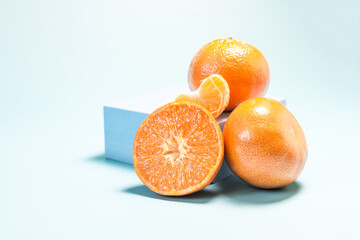 Tangerines and tangerine slices in close-up with blue decor on a light blue background in natural light.