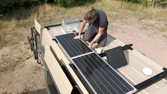 Person working on a solar panel on the roof of a caravan