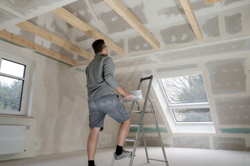 Man plastering drywall in a private house.. - obrazy, fototapety, plakaty