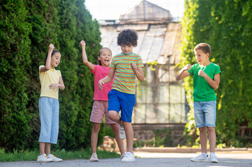 Curly-haired boy with cheerful friends in park