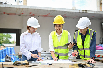 Asian female architect checking details on blueprint during meeting with an engineers