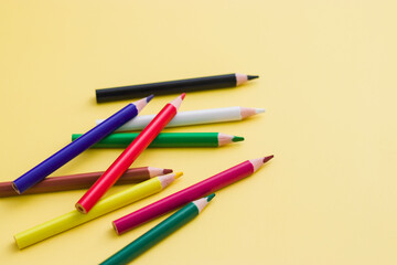 background from color pencils on yellow paper. Crayons - colored pencil set loosely arranged on yellow background. colored pencils are not arranged exactly in a row.