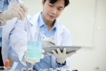 Handsome Asian male scientist working in the lab, recording the experiment results on tablet