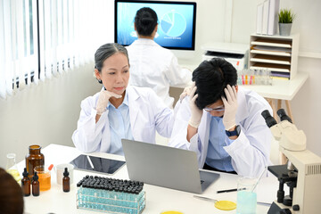Fototapeta premium Stressed and serious Asian male scientist upset with his medical experiment project