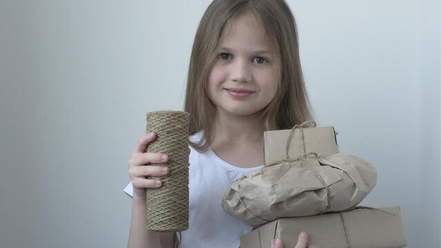 Gift wrapping. Little girl holding zero waste gifts in craft paper
