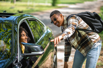 African american man in plaid shirt asking a female driver to take him to the city