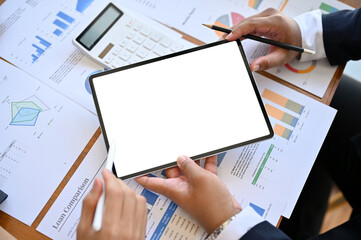Fototapeta na wymiar Top view, A businessman holding a tablet white screen mockup over the financial meeting table.