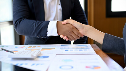 An Asian businesswoman shakes hands with an African partner during a business meeting