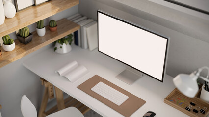 A modern office desk workspace with computer mockup and decor on white table. above view