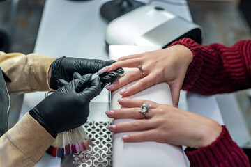 a professional nail extension master selects a color for his client during an epidemic.