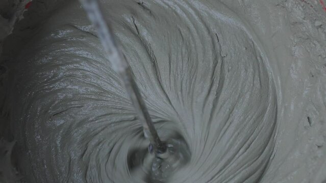 The mortar is kneaded in a bucket with a mixer. Mixing mortar in a bucket close-up.