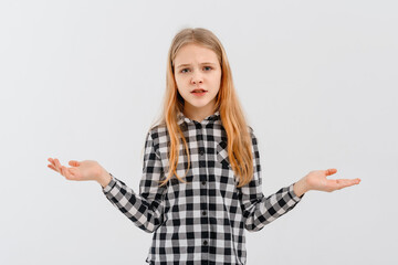 Clueless teen girl shrugs shoulders, smiles nervously, saying sorry, dont know, have nothing, standing confused against white background