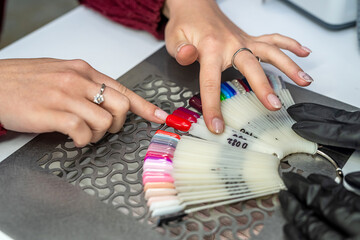 female client chooses colored lacquers in palette at salon