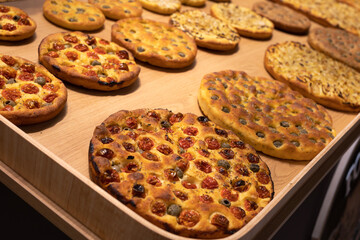 Round Flatbreads displayed in Bakery filled with Oregano, Tomatoes and Olives