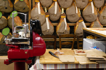 Red Slicer and Group of Whole Raw Hams hung on a Wall