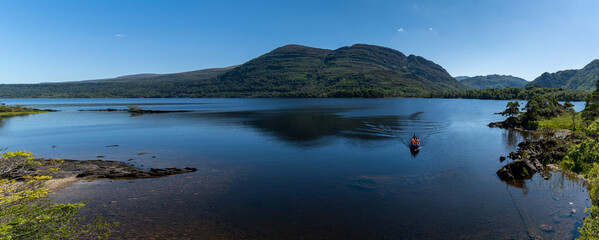 tourists enjoy a boat ride on Muckross Lake in Killarney National Park on a beautiful summer day