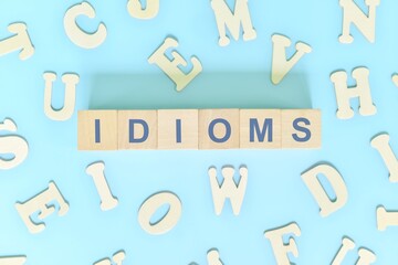 Idioms or idiom concept in English grammar class lesson. Wooden blocks typography flat lay in blue...