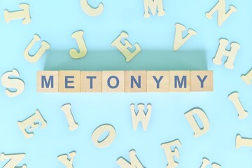 Metonymy figure of speech concept in English grammar class lesson. Wooden blocks typography flat lay in blue background.