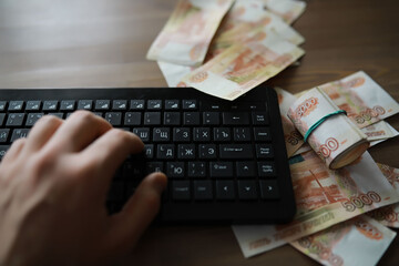 Stacks of 5000 ruble banknotes on the table next to the laptop. Savings and investments in the...
