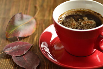 Сup of black coffee with red leaves. Fall composition.