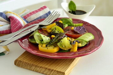 Colorful tomatoes salad with eggplant, cucumber, corn and basil