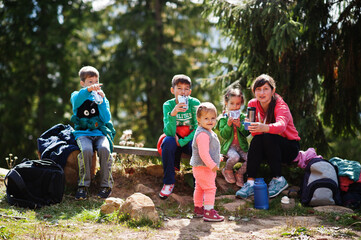 Mother with four kids resting in mountains. Travel and hiking with childrens. Drinking tea in nature.