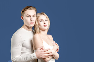 Young couple posing in the studio on a blue background.