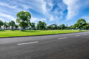 Asphalt road and green trees with grass background