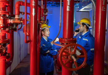 An engineer in the fire protection pump room talking with walkie talkie checking and operate trouble shooting defective spray nozzle head valve at the red pipeline

