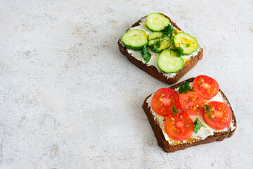 slices of bread with cucumber and tomatoes isolated on concrete background
