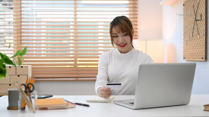 Pretty woman with credit card and purchasing product via online shopping on laptop. Online shopping, internet banking concept