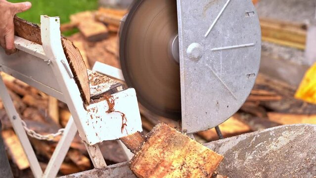 Slow motion crosscut saw cutting firewood from wooden pine planks - Closeup of saw and wood falling into wheelbarrow in 20 percent slow motion and blurred background
