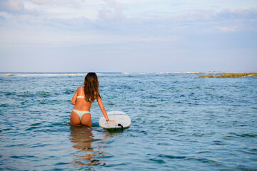 surfer girl at the Cloud 9 pier with her surfboard looking at the horizon