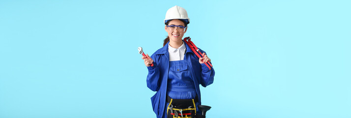 Female plumber with tools on light blue background