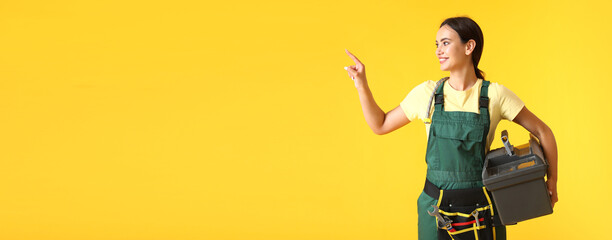 Female worker with tools bag pointing at something on yellow background with space for text