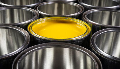 Yellow color emulsion paint tin closeup with empty tins - concept of individual