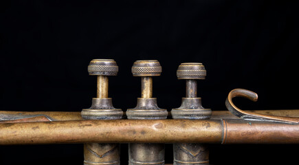 Closeup view of trumpet valves with golden color and black background