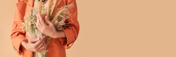 Woman holding bouquet of dry flowers and branches on beige background with space for text, closeup