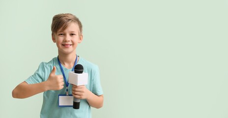Little journalist with microphone showing thumb-up on color background with space for text
