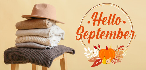 Text HELLO SEPTEMBER and stylish autumn clothes with hat on beige background