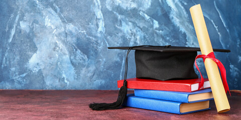 Graduation hat, diploma and books on table